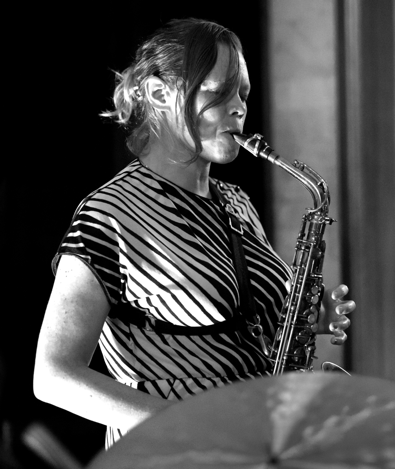 Alto saxophonist in a striped dress, eyes closed, playing